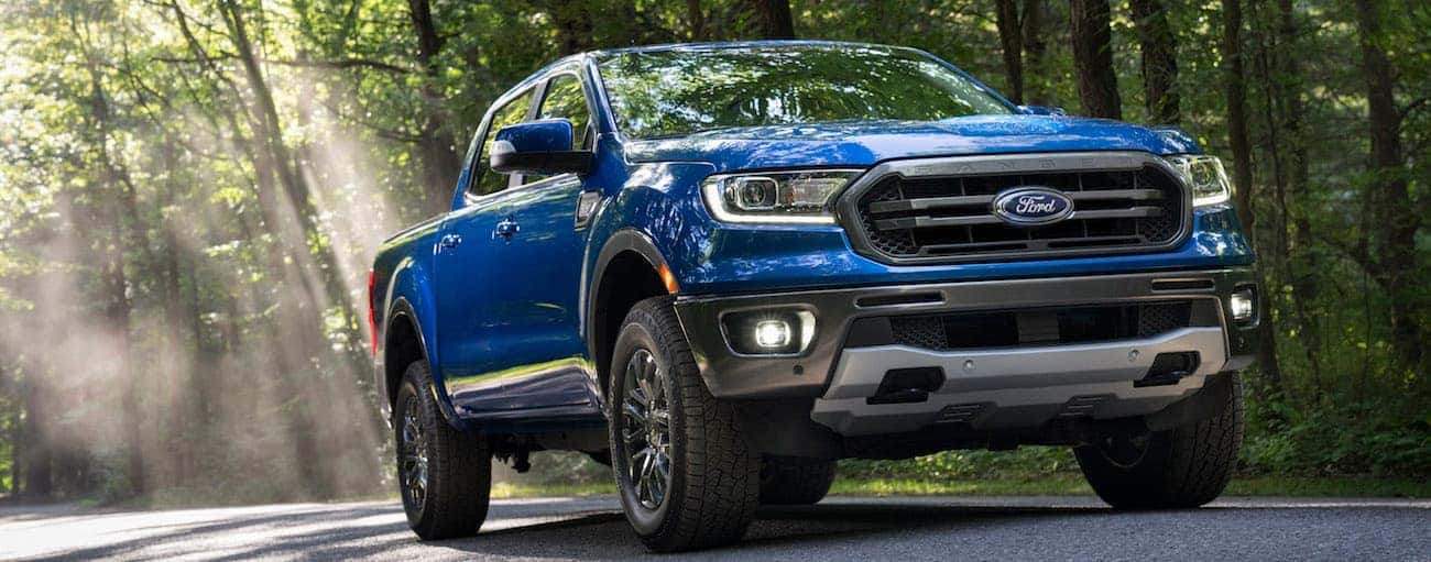 A blue 2020 Ford Ranger is driving on a shaded treelined road near Cincinnati, OH.