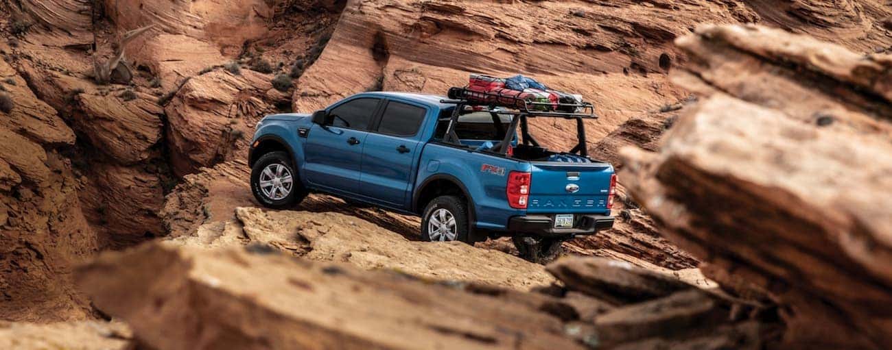 A blue 2020 Ford Ranger is shown off-roading on desert rocks.