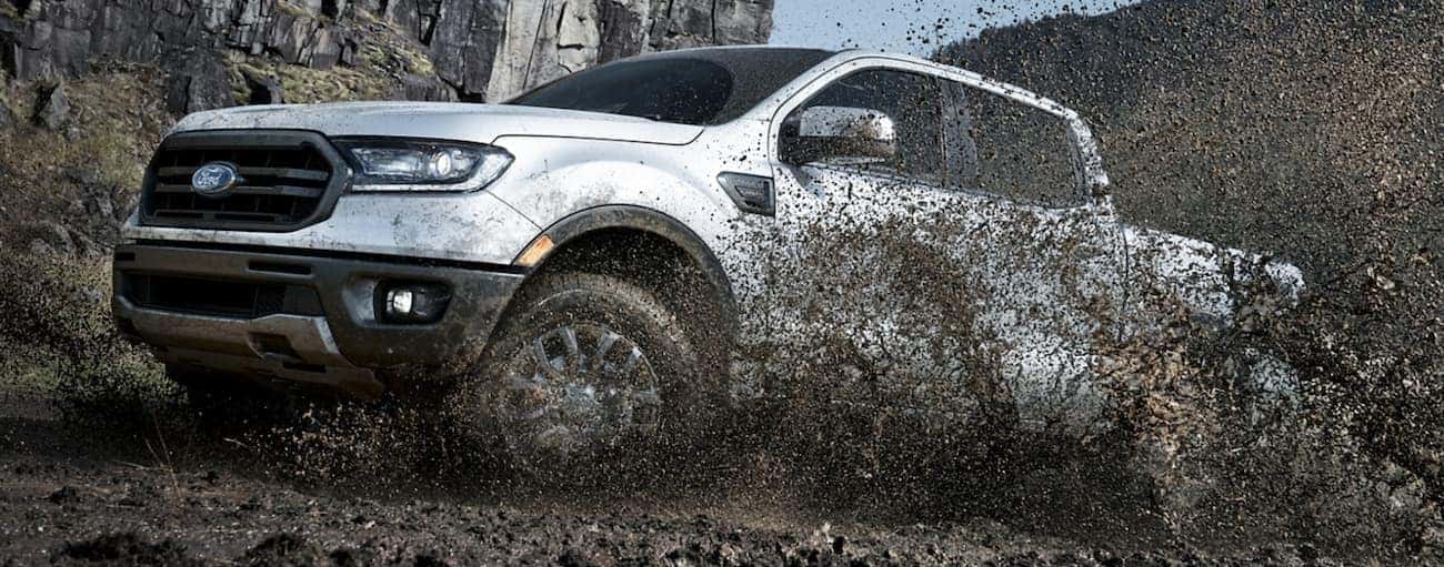 A white 2020 Ford Ranger, which wins when comparing the 2020 Ford Ranger vs 2020 Jeep Gladiator, is spraying mud off-road near Cincinnati, OH.