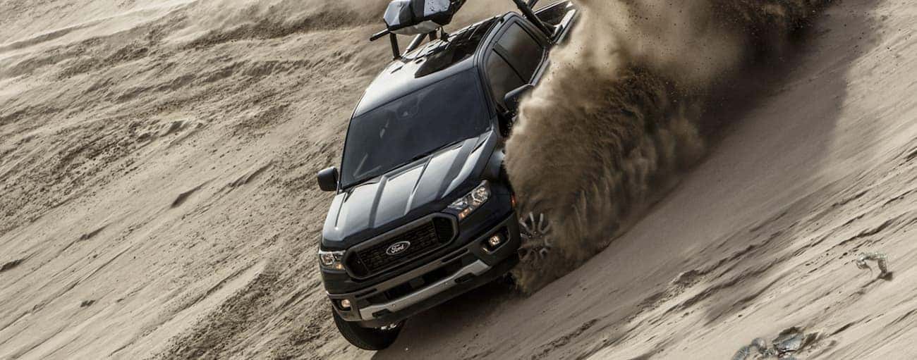 A black 2020 Ford Ranger, which wins when comparing the 2020 Ford Ranger vs 2020 Nissan Frontier, is driving down a sand hill.