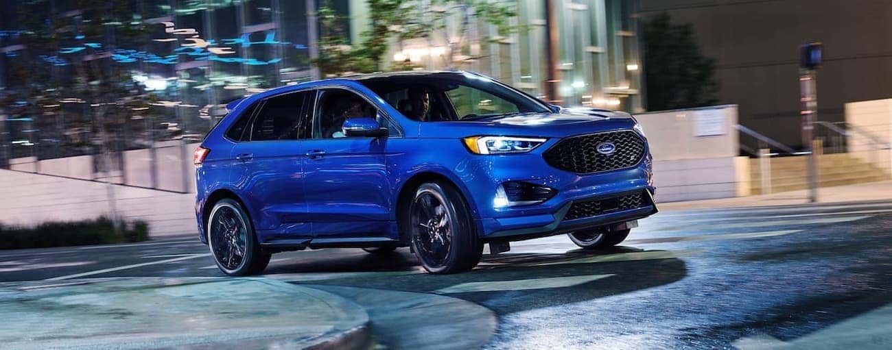 A blue 2020 Ford Edge ST is driving on a Cincinnati, OH, street at night.