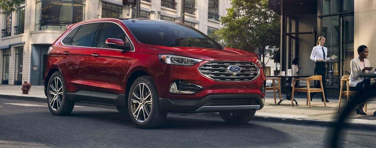 A red 2020 Ford Edge Titanium is driving past a Cincinnati, OH, cafe.