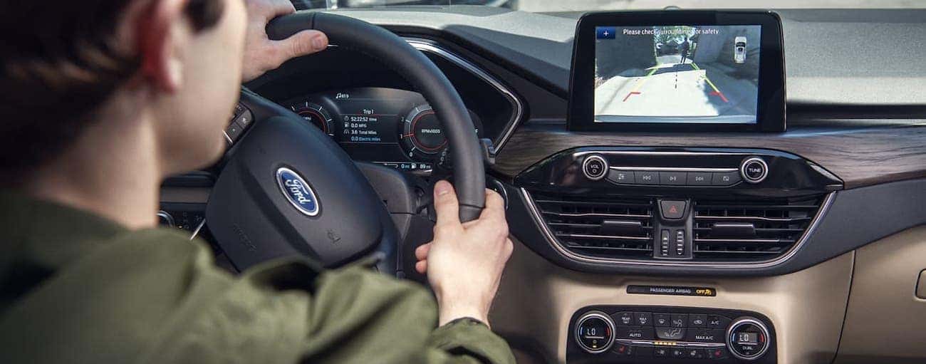 A view over the driver's shoulder of the back up camera in action inside a 2020 Ford Escape.