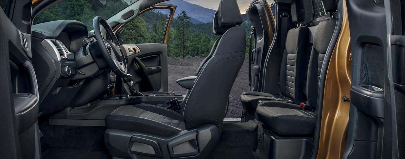 The side of an orange 2020 Ford Ranger is shown with both doors open to see the black interior.