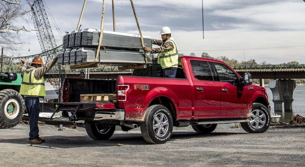 Workers are loading building materials in the bed of a red 2020 Ford F-150 near a river in Cincinnati, OH.