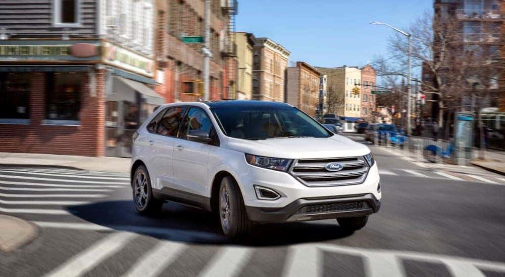 A white 2018 Ford Edge is driving on a city street near Cincinnati, OH.