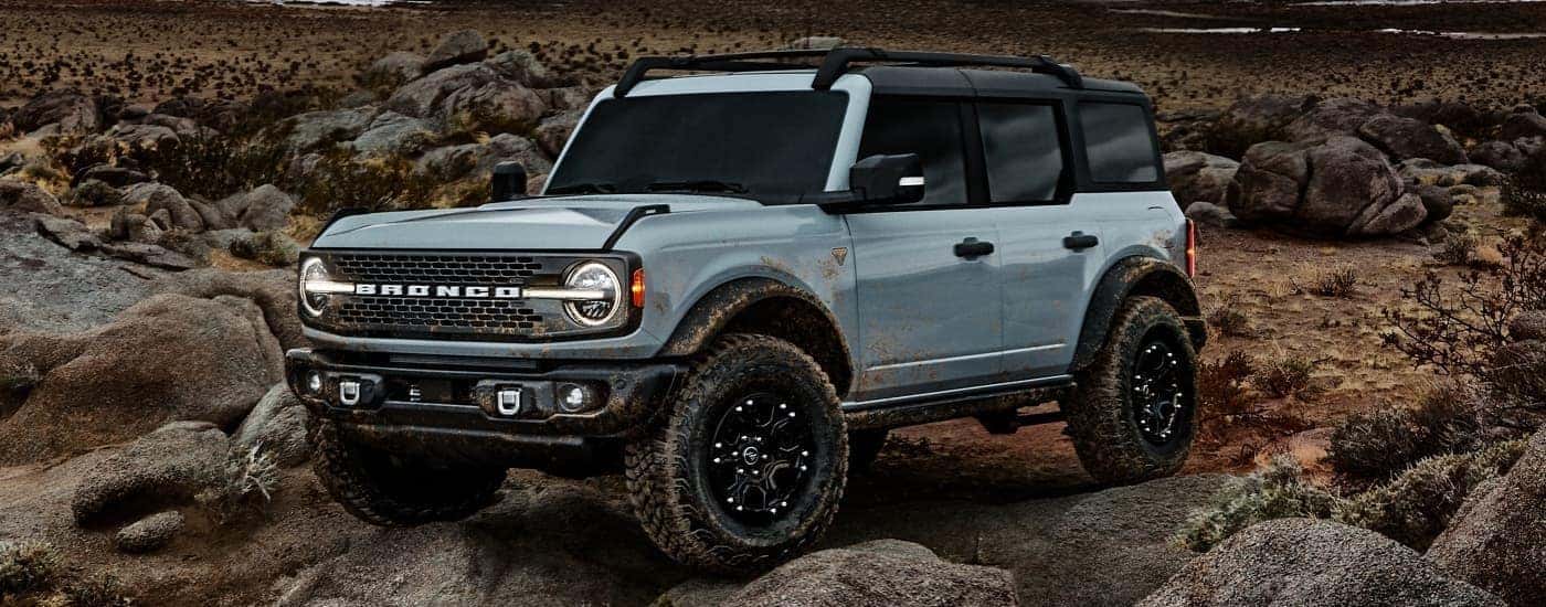 A light blue 2021 Ford Bronco four-door is crawling over rocks as part of the 2021 Ford Bronco vs 2021 Ford Bronco Sport comparison.