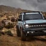 A blue 2021 Ford Bronco 4-door is shown from the front while driving in a desert.