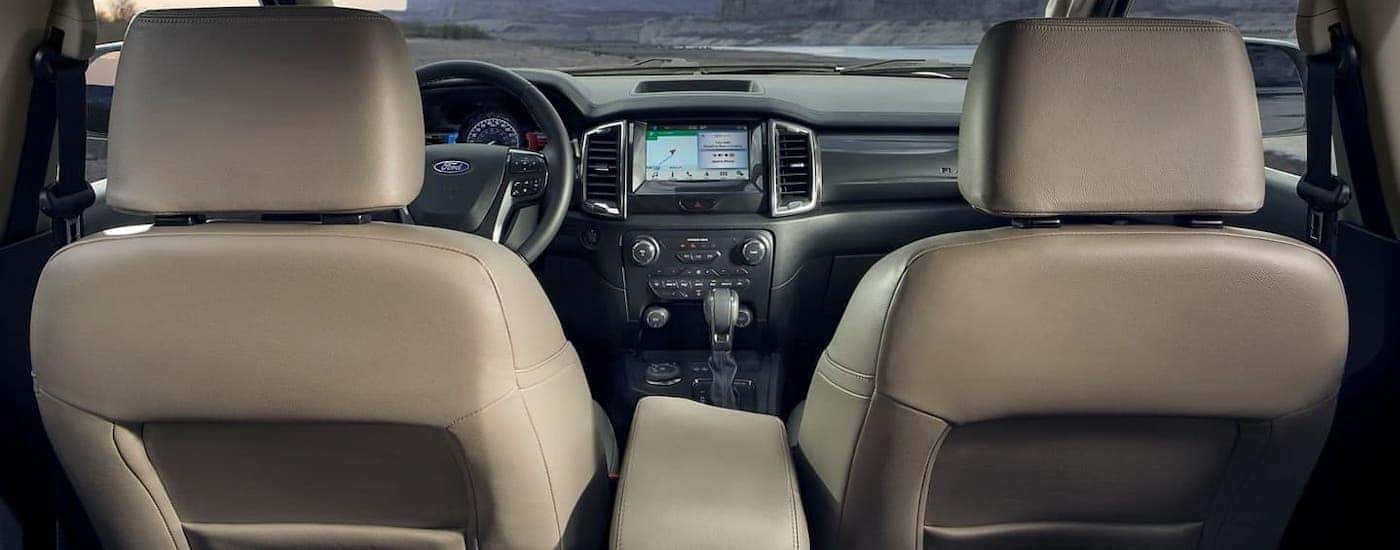 The gray interior of a 2021 Ford Ranger is shown from the rear seat facing the dashboard.