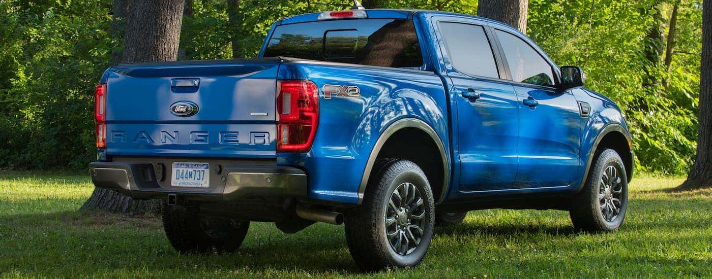 A blue 2021 Ford Ranger FX2 is shown from the rear while parked on grass in front of trees.