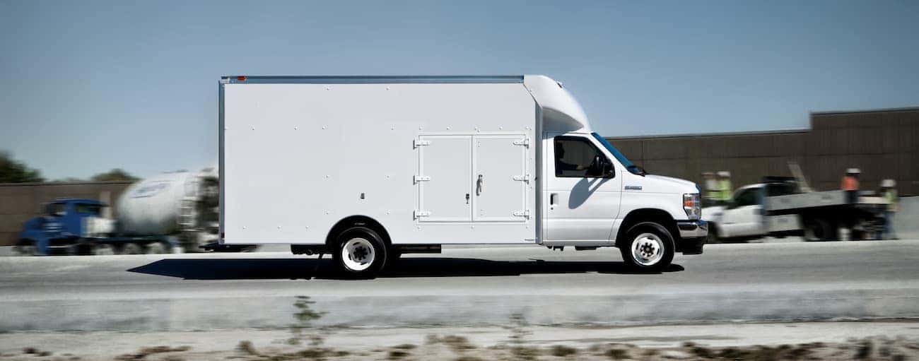 A white 2021 Ford E-Series is shown from the side on a rural road.