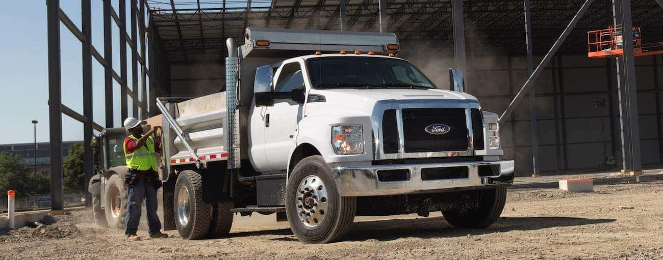 A white 2021 Ford Maximum Duty with a dump body is at a construction site.