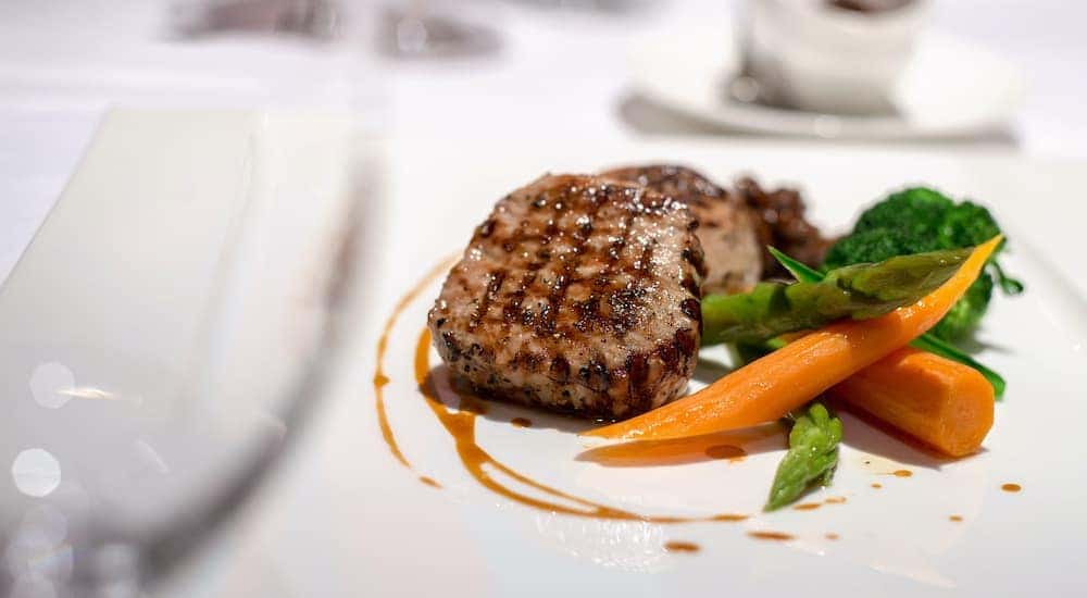 A close up is shown of a steak and vegetables on a white plate at a restaurant in Cincinnati, OH.