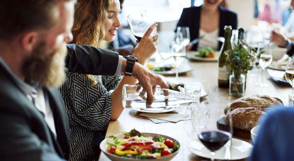A man in a suit is pouring a glass of water at an Italian restaurant.