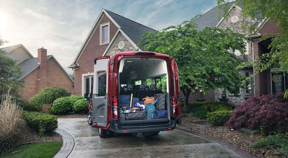 A red 2020 Ford Transit is shown in a driveway with the rear doors open full of cargo.