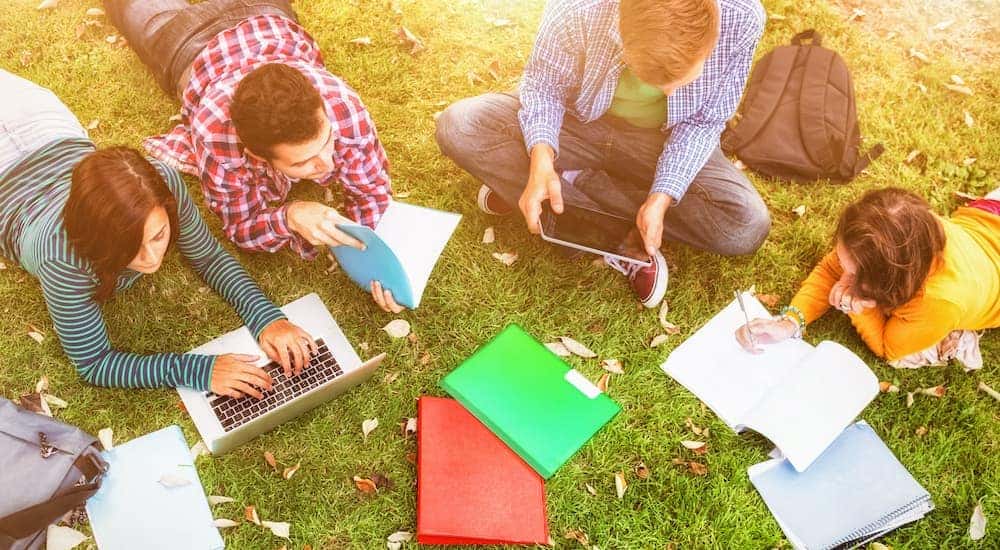 An aerial view is showing a group of college students studying on the grass.