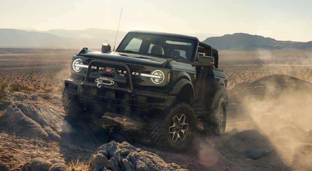 A black 2021 Ford Bronco 2 Door is off-roading on desert rocks.