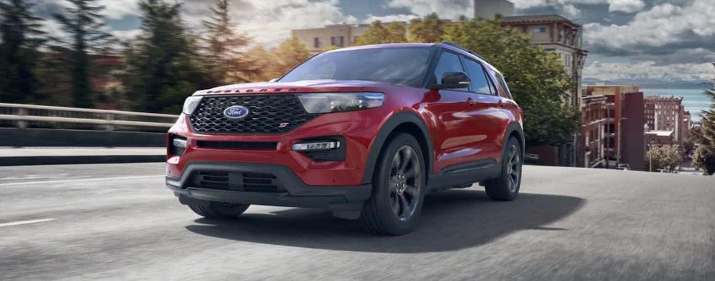 A red 2021 Ford Explorer is driving on a multi-lane road in a city.