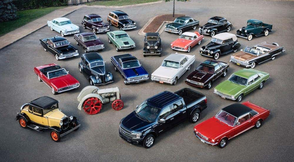 Many antique Ford vehicles are shown from above in a parking lot.