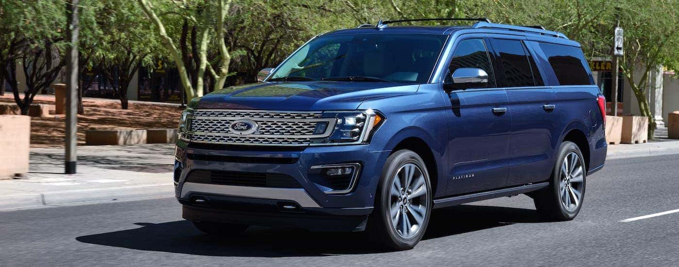 A blue 2020 Ford Expedition Platinum is driving on a suburban street.