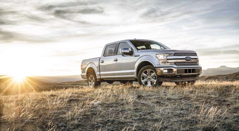 A silver 2018 Ford F-150 is parked in a field at sunset.
