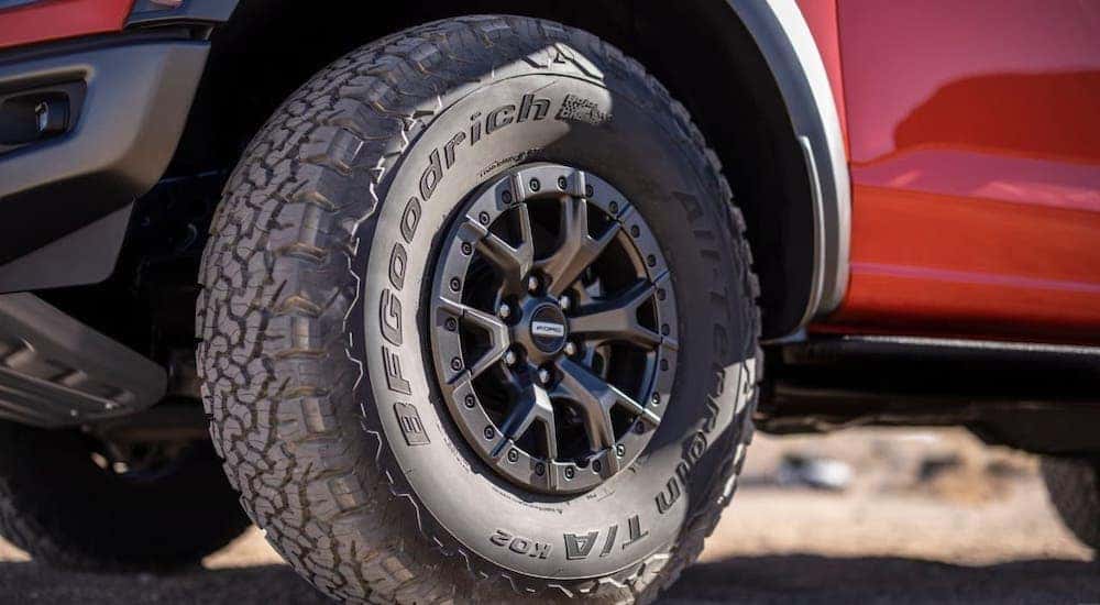 A closeup shows the tire on a red 2021 Ford F-150 Raptor.