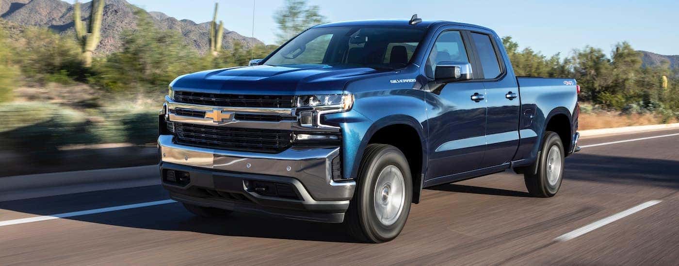 A blue 2019 Chevy Silverado 1500 is driving on a desert highway.
