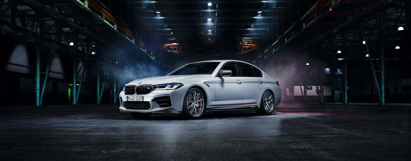 A white 2021 BMW M5 is shown in a warehouse. 