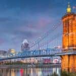 A bridge is lit up over a Cincinnati river at dusk.
