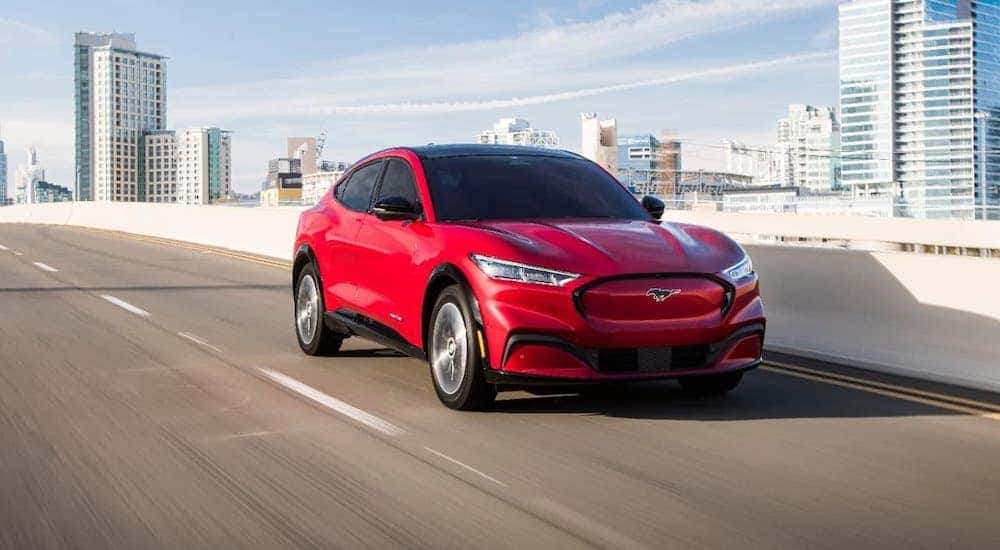 A red 2021 Ford Mustang Mach-E is driving on a highway after leaving a Ford dealer in Cincinnati.