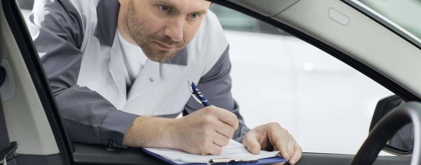 A man with a clipboard is shown inspecting a Ford end of lease vehicle.