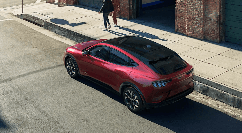 A red 2021 Ford Mustang Mach-E is parked on a city street.