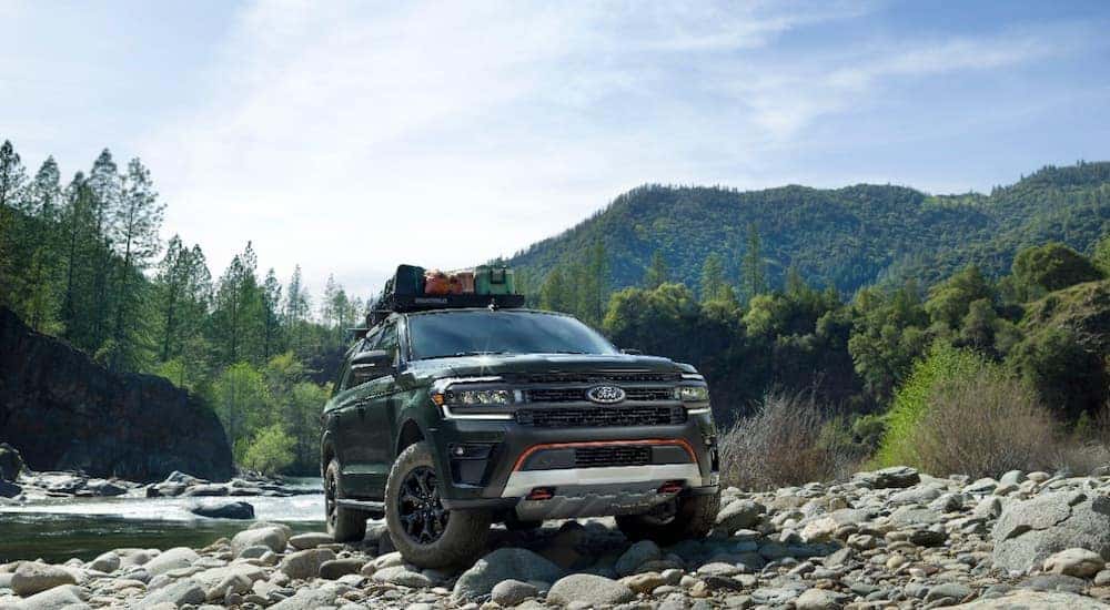 A green 2022 Ford Expedition is shown parked on rocks near a river.
