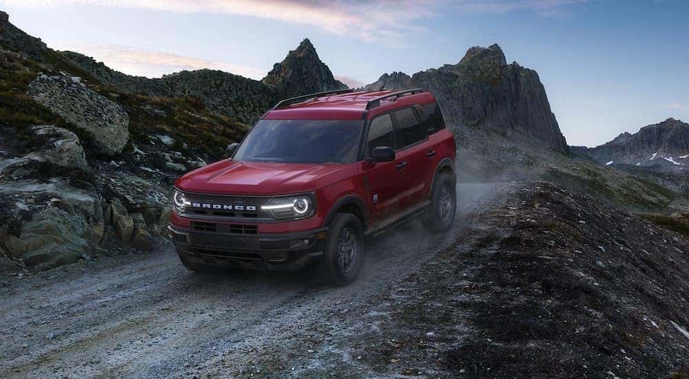 A red 2022 Ford Bronco Sport is shown driving down a dirt road.