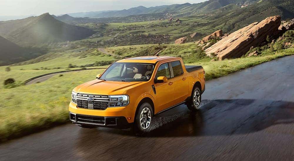 An orange 2022 Ford Maverick is shown driving after going through the Ford pre-order process at a dealership.