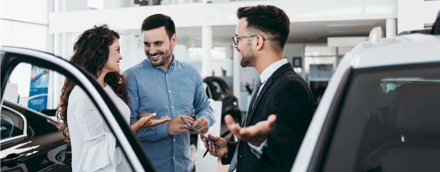 A salesman is shown discussing vehicles with customers at a certified pre-owned Ford dealer.