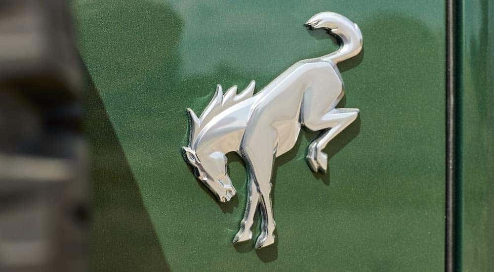 A close up shows the Bronco badge on green 2023 Ford Bronco Hybrid.
