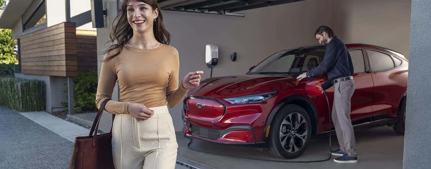 A red 2022 Ford Mustang Mach-E is shown in a driveway charging.