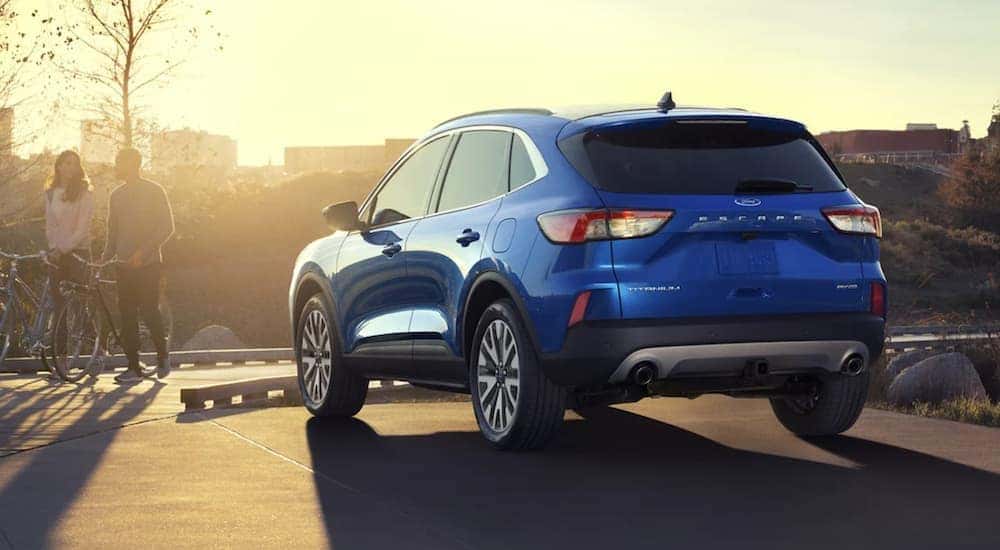 A blue 2021 Ford Escape Hybrid is shown from the rear parked in a lot at sunset.
