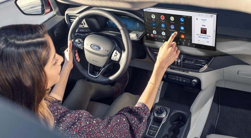 A woman using the infotainment screen in a 2023 Ford Escape for sale. 