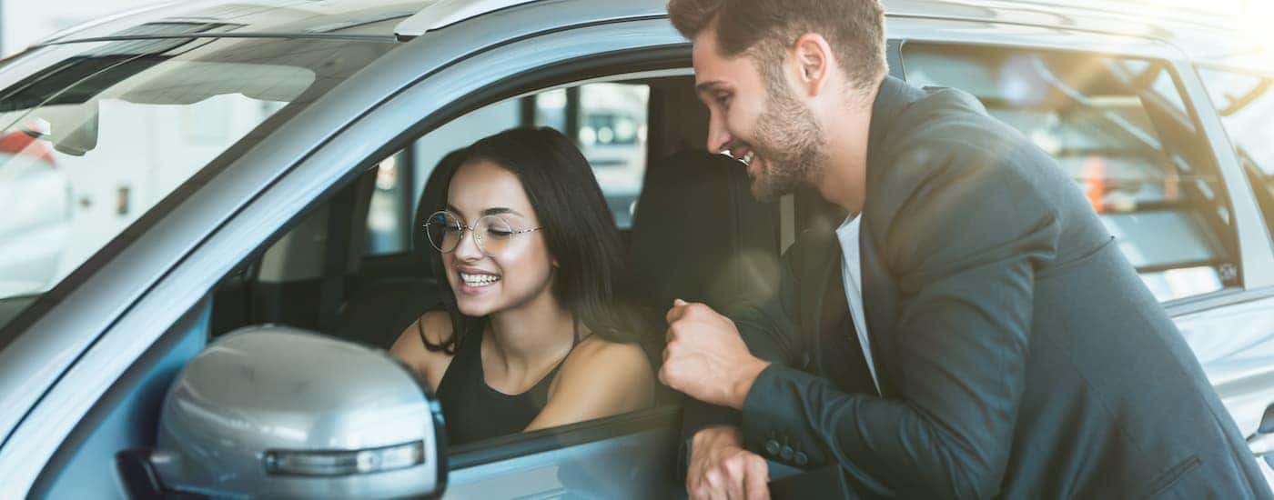A person is shown smiling while they 'sell my car' at a dealership.