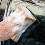 man washing window of car