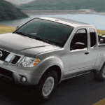 white nissan frontier truck towing car on trailer
