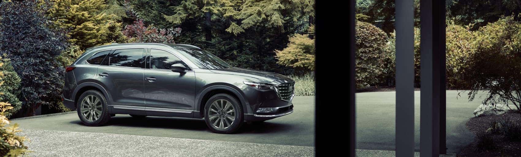 2021 Mazda CX-9 profile shot parked in driveway of woodsy home