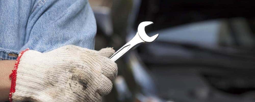 Auto service tech wearing a glove and holding a wrench