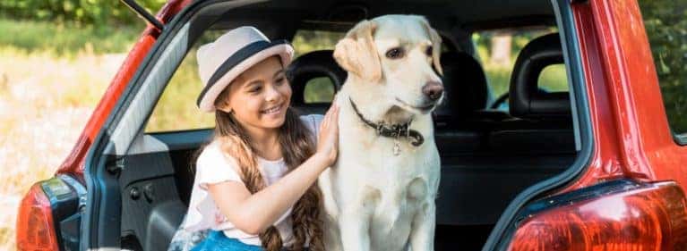 Girl with dog in the trunk of a SUV