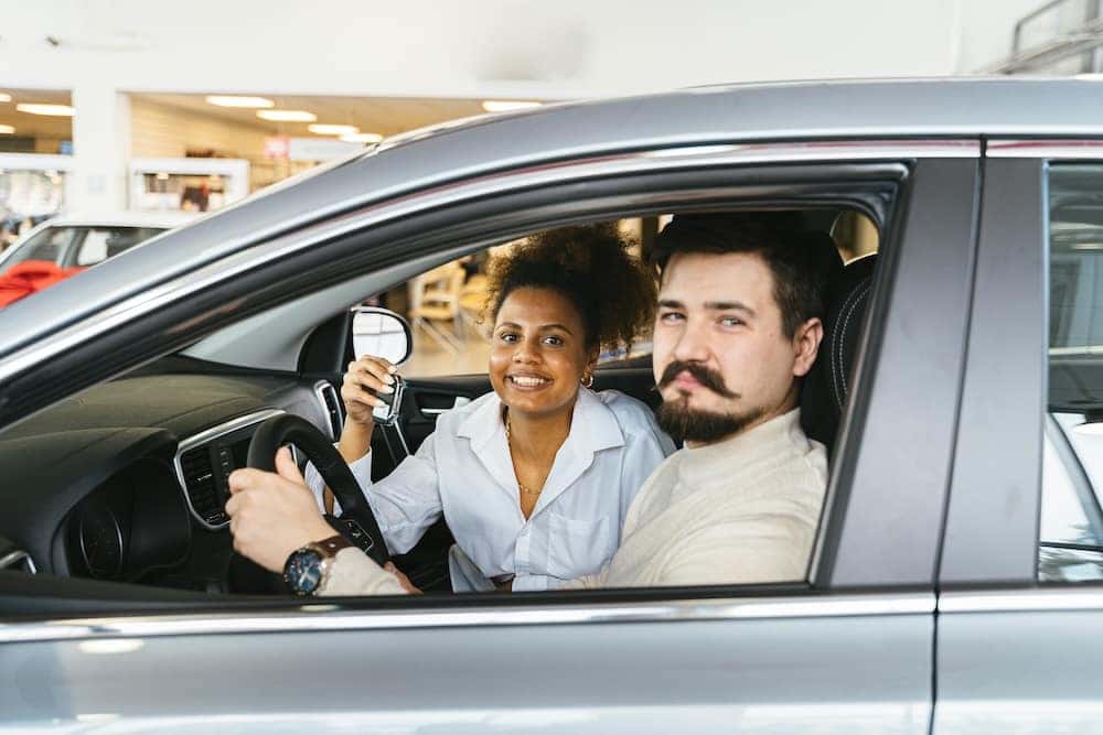 Man and women sitting in their new car after car shopping