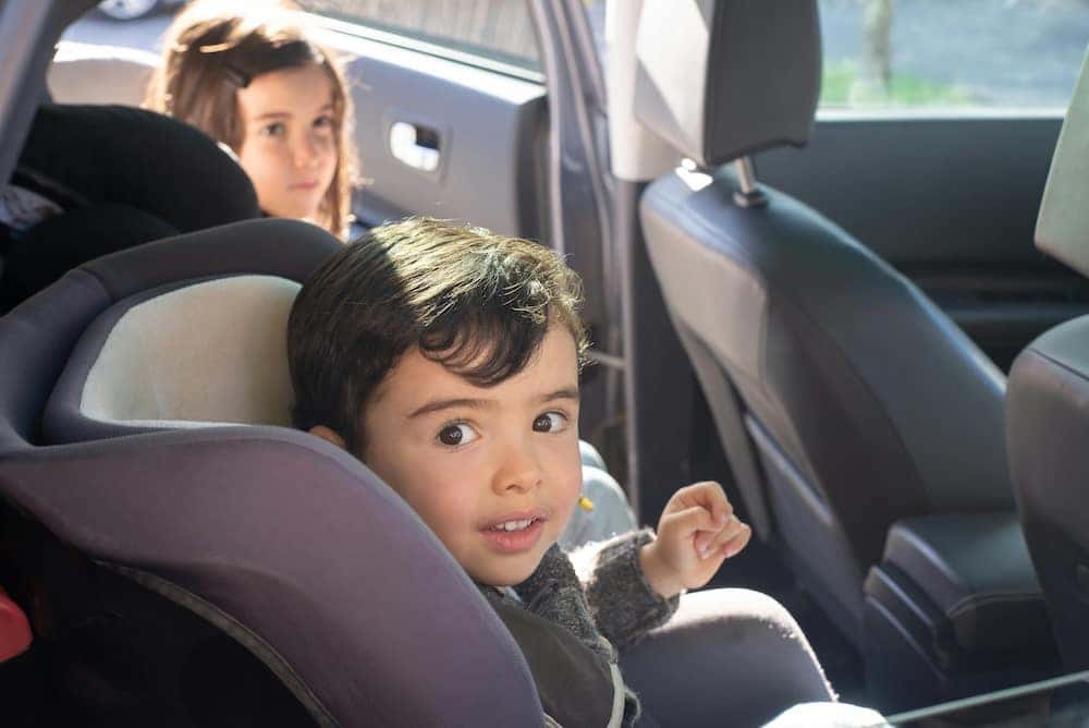 Little boy sitting in carseat and little girl getting into car. Best family SUVs. Safe Family SUV.