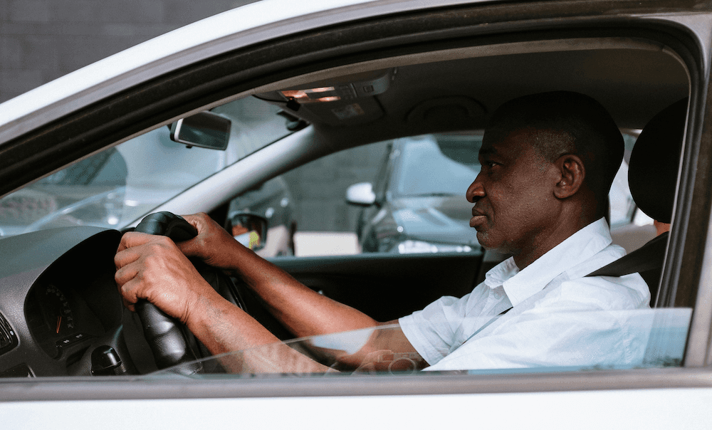 A man driving a used car with the windows down
