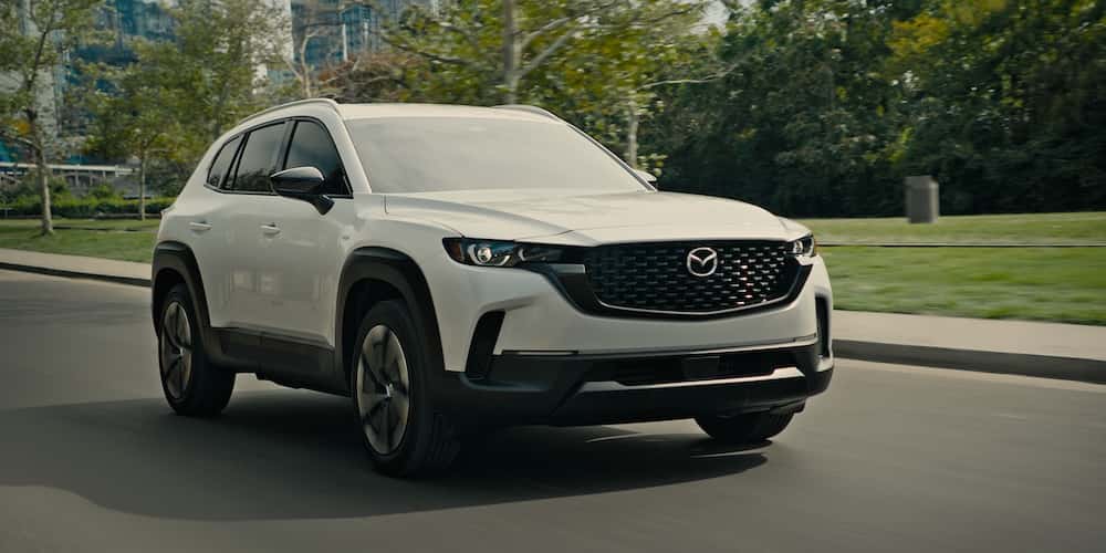 Mazda SUV driving along a tree-lined street